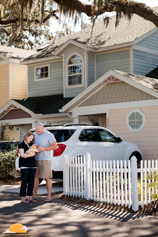 family in front of home family and white picket fence